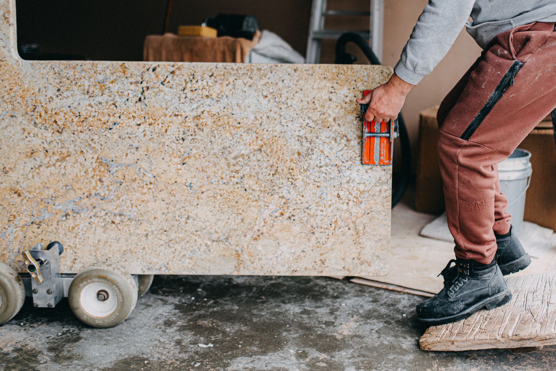 A man pushing a granite countertop, holding it with an orange handle