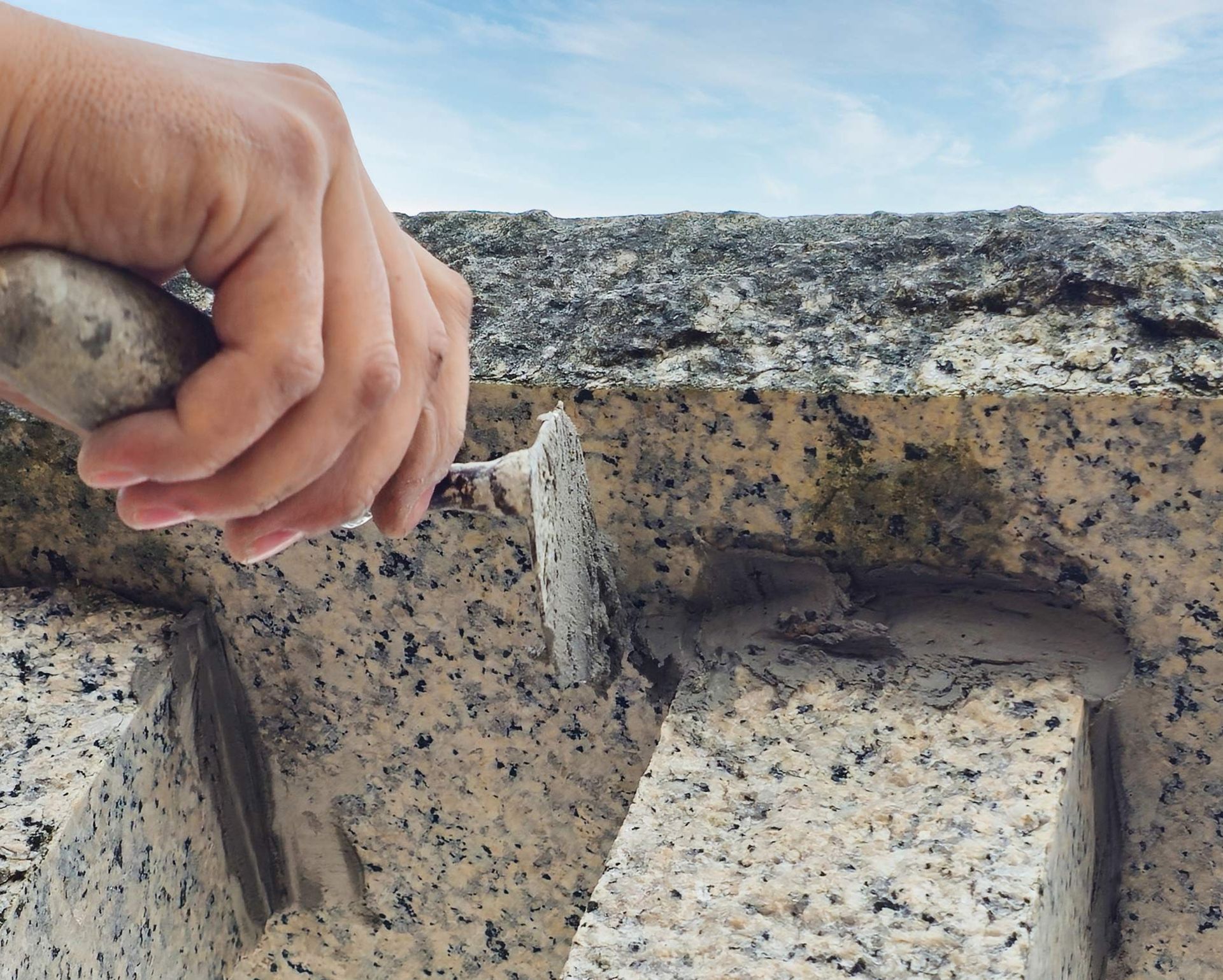 Construction worker filling the joints of the granite wall. Construction worker filling the joints of the granite wall.