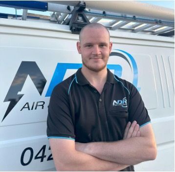 Man with crossed arms in front of a white van with "ADR AIR" logo; wearing black polo shirt. — NDR Trade Solutions in Robina, QLD