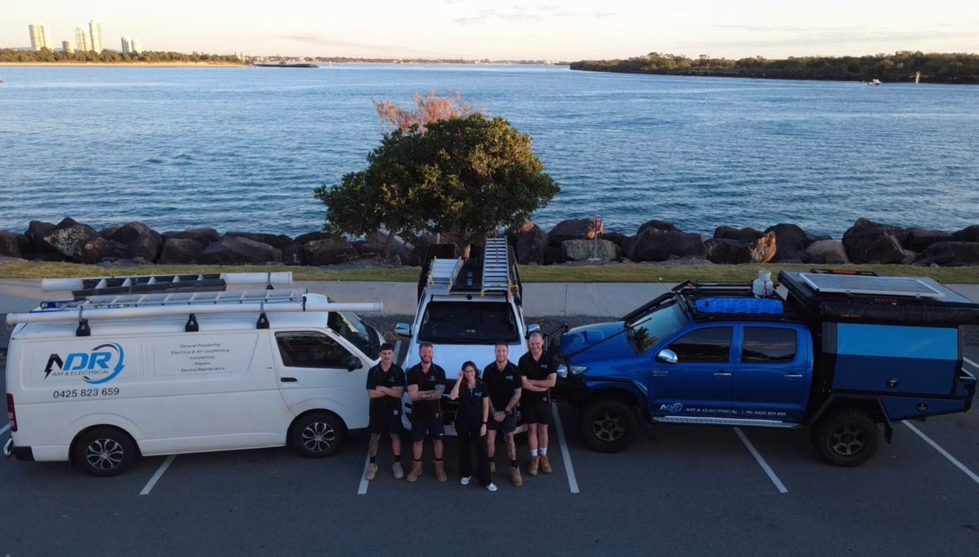 Group of People and Three Work Vehicles Posed by Water — NDR Trade Solutions in Robina, QLD