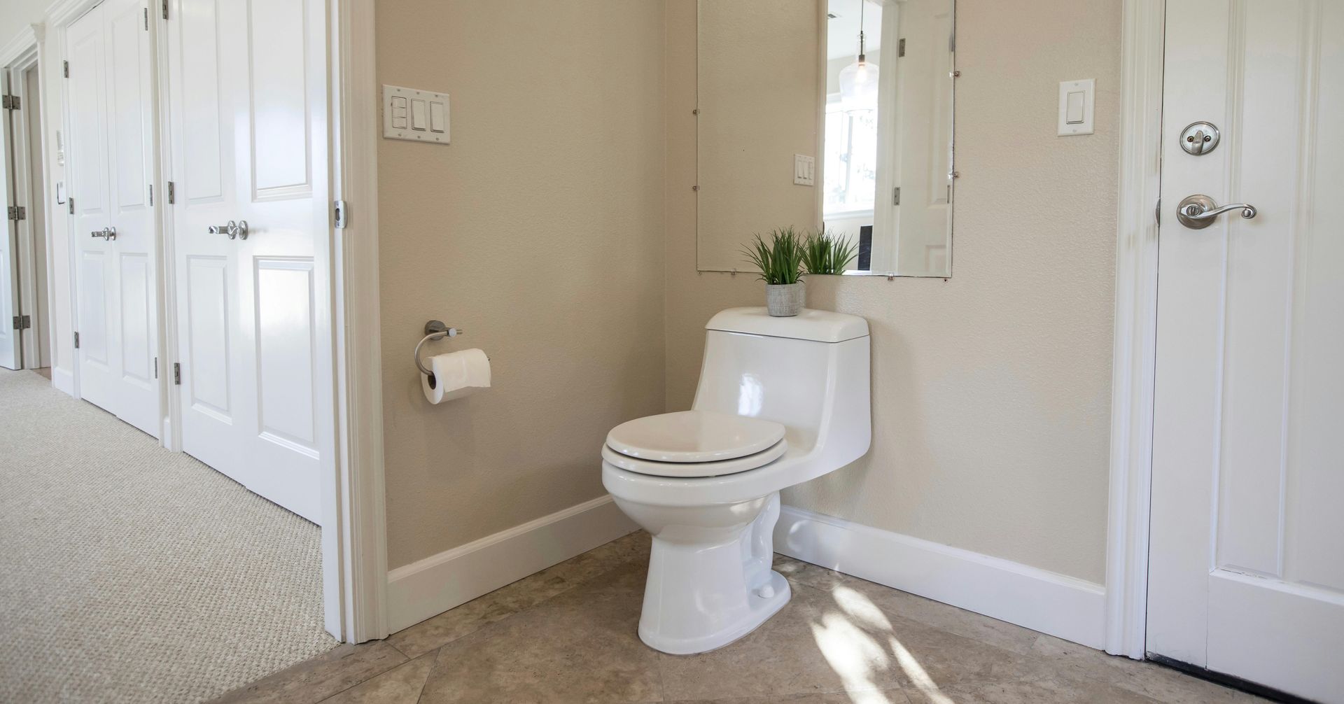 A modern bathroom featuring a white tub, wall-mounted toilet with a bison decor piece, and teal subway tile accents.