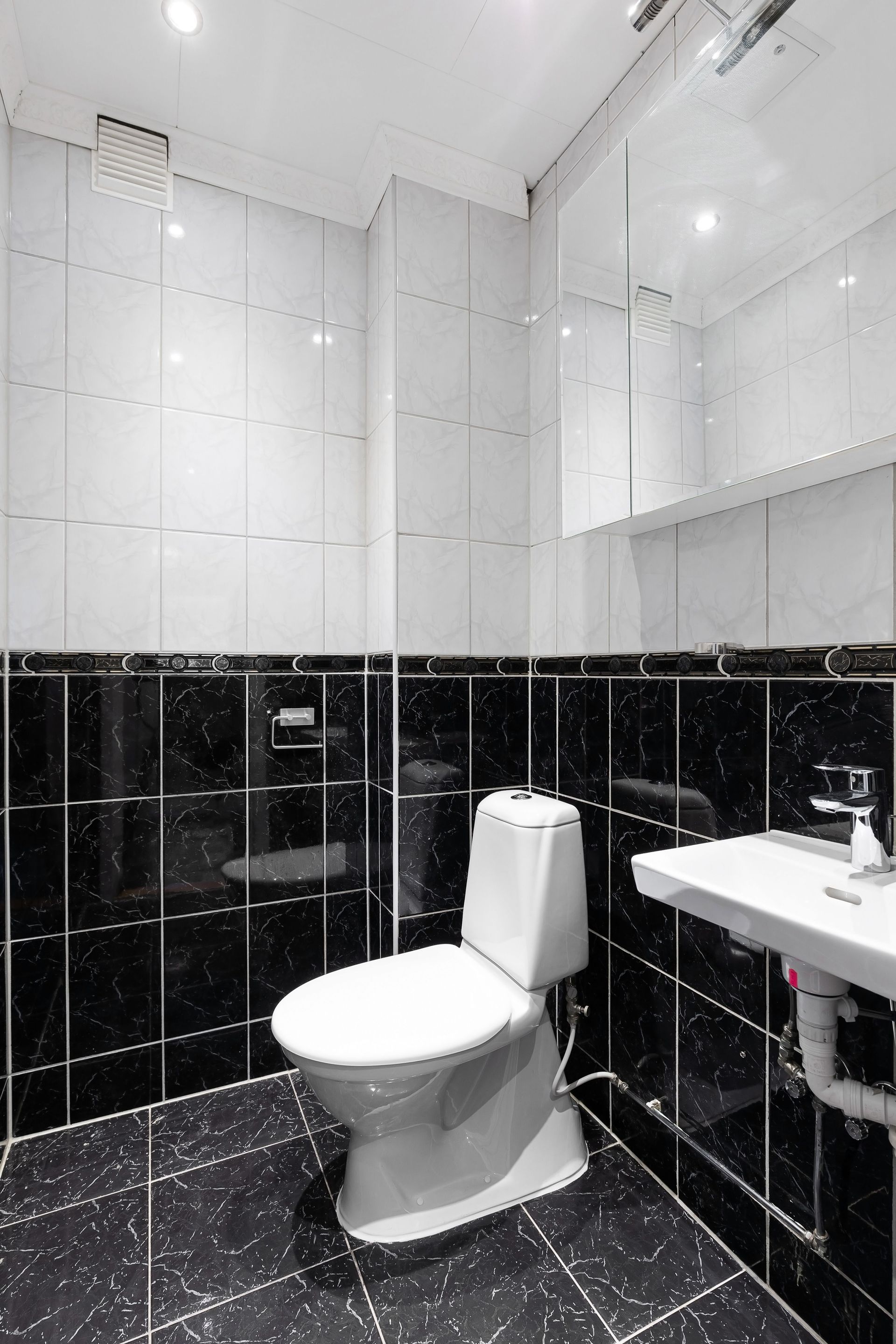 A modern bathroom featuring a white tub, wall-mounted toilet with a bison decor piece, and teal subway tile accents.