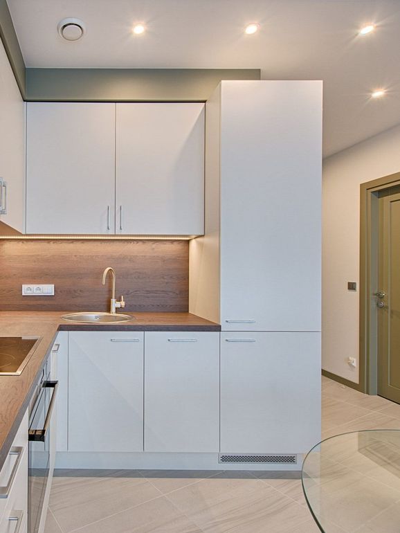 A kitchen with white cabinets , a sink , and a refrigerator.