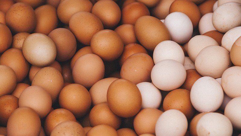 uma pilha de ovos marrons e brancos estão empilhados uns sobre os outros.