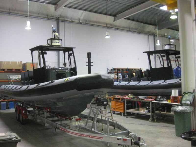 Two boats are sitting on a trailer in a garage