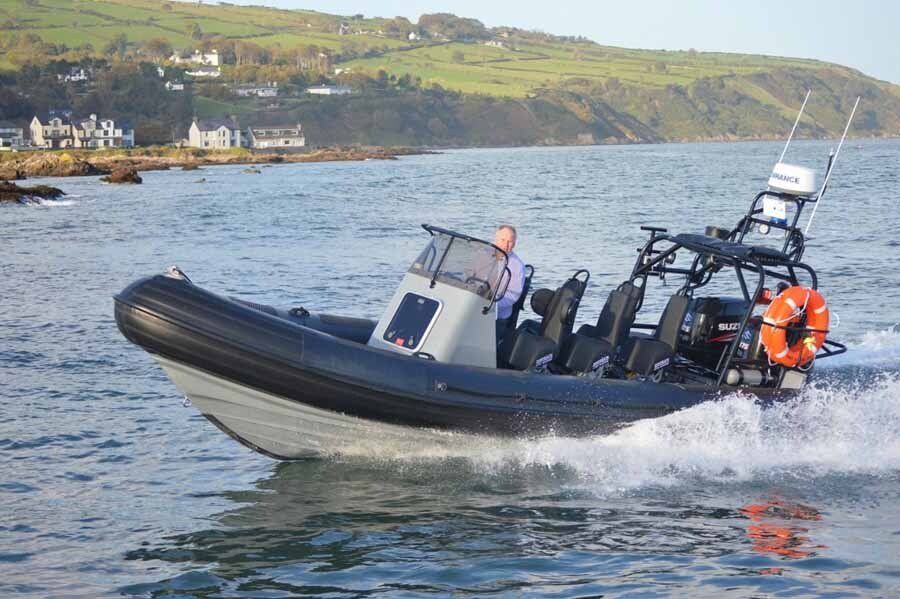 A man is driving a boat on a body of water.