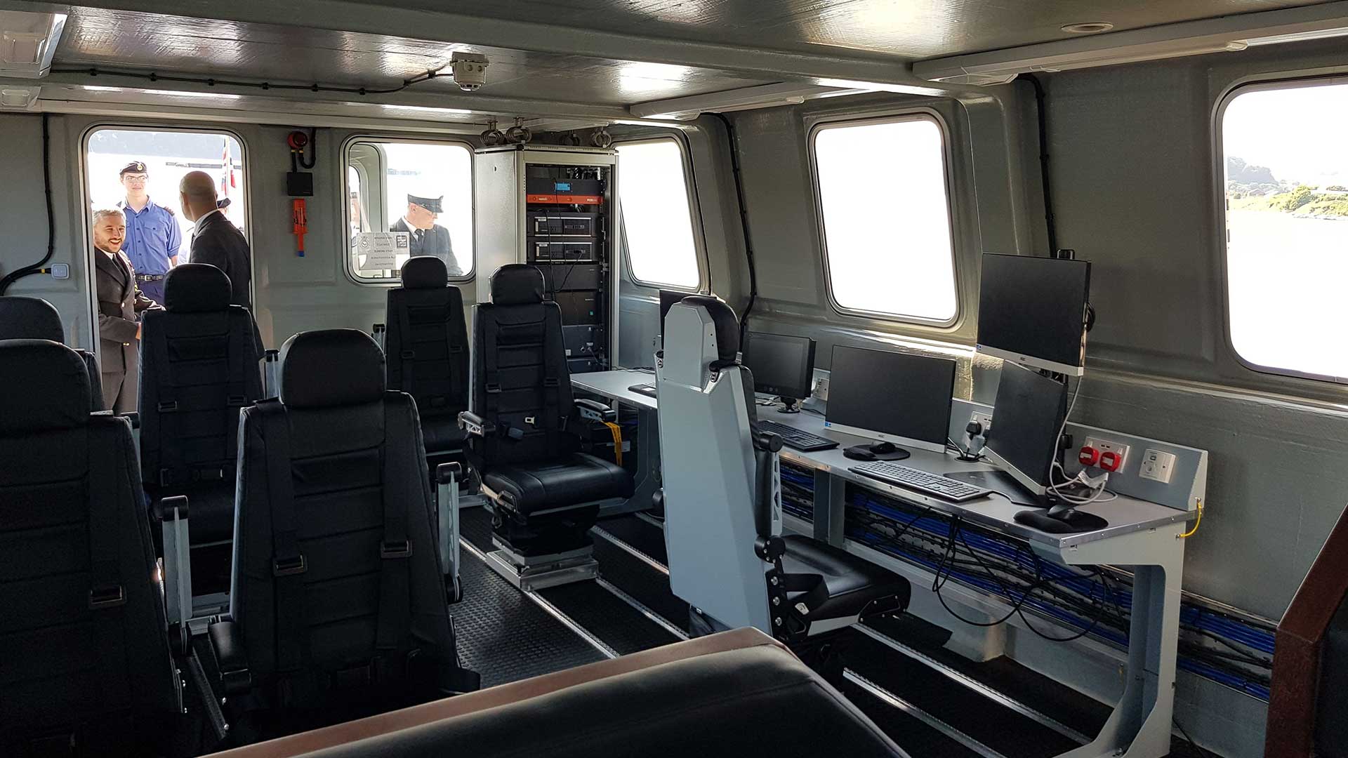 The inside of a boat with a lot of seats and computers.