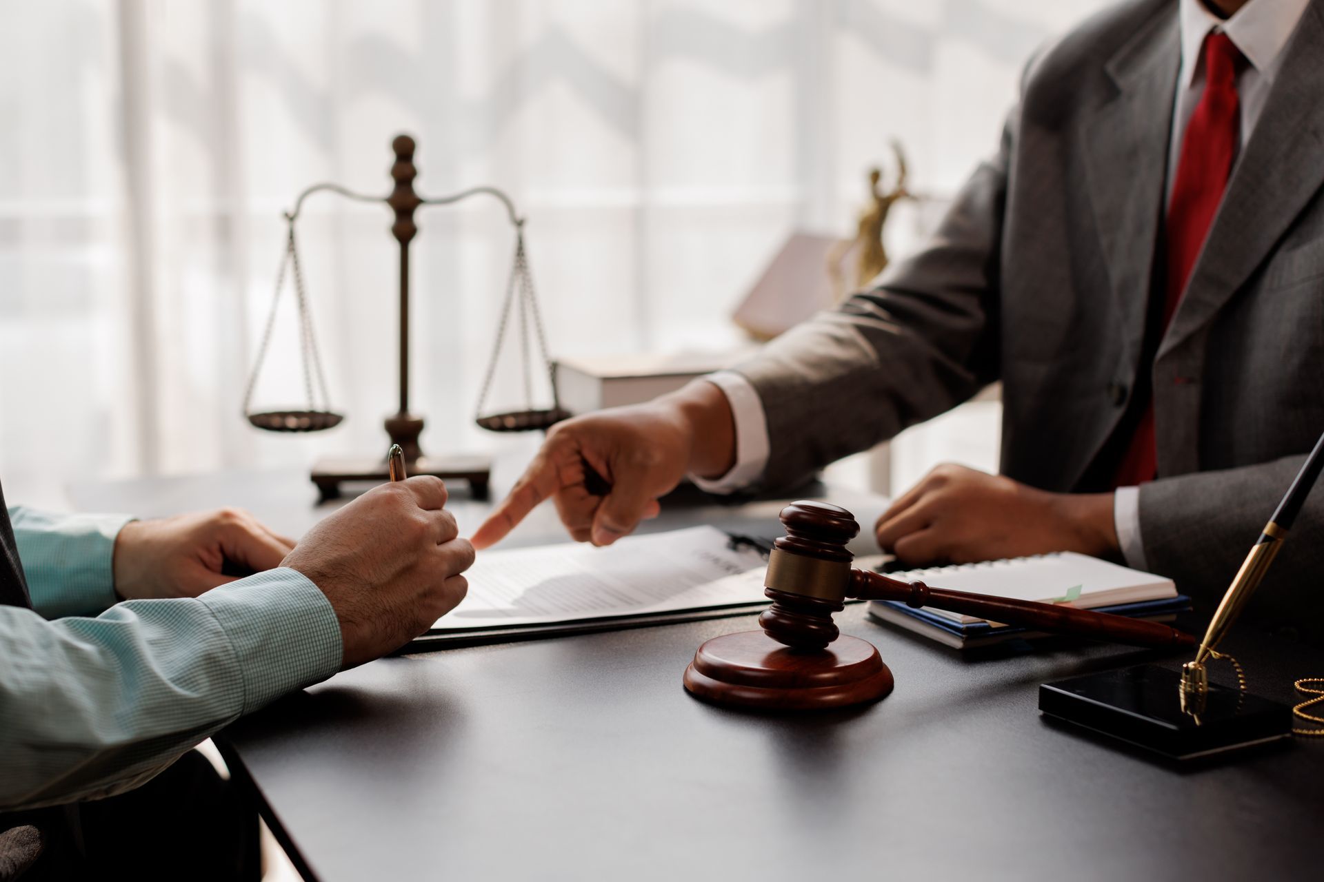 Attorney reviewing legal contract with client at law office desk with gavel and scales.