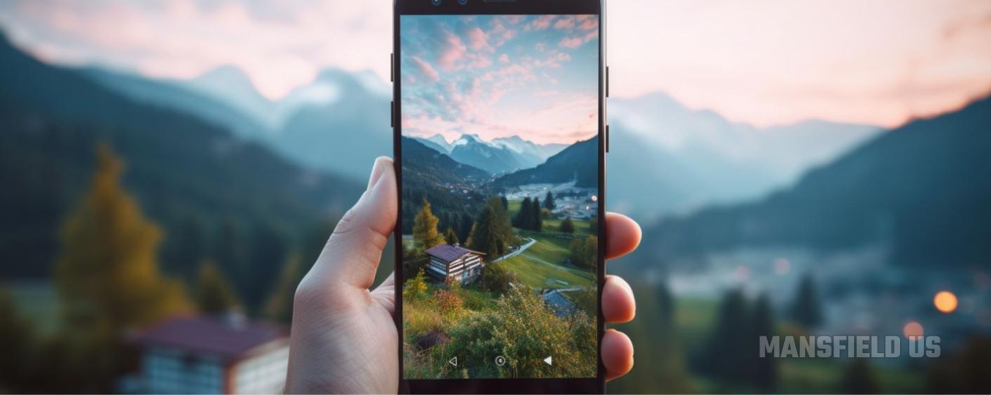 a person is holding a cell phone in their hand and taking a picture of a mountain landscape .