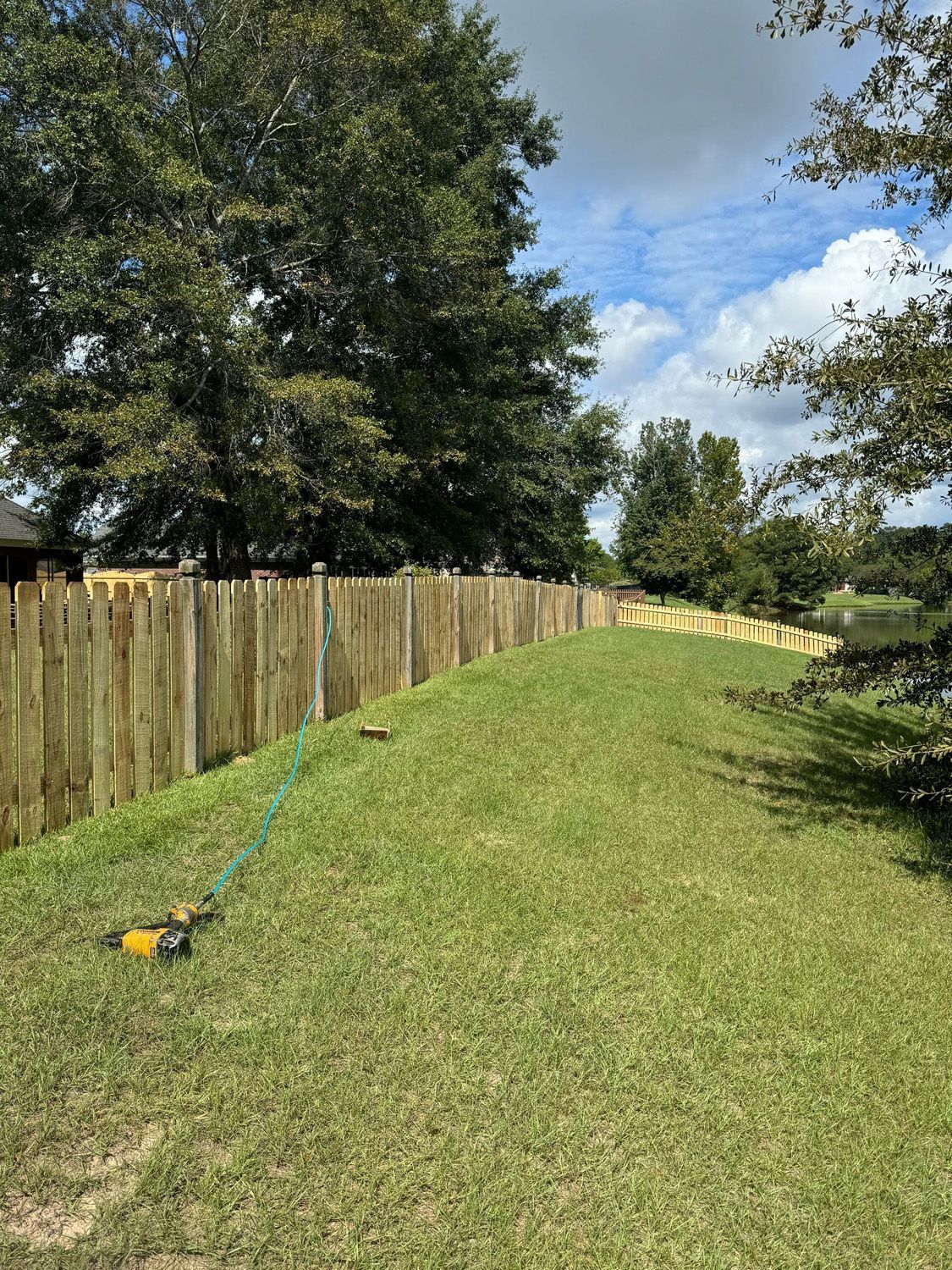 A wooden fence surrounds a lush green field.
