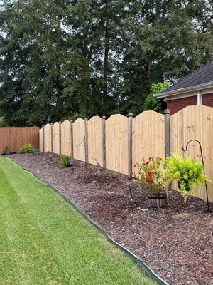 A wooden fence is in the backyard of a house.