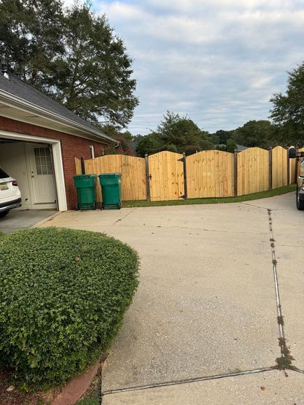 A wooden fence is surrounding a driveway next to a garage.