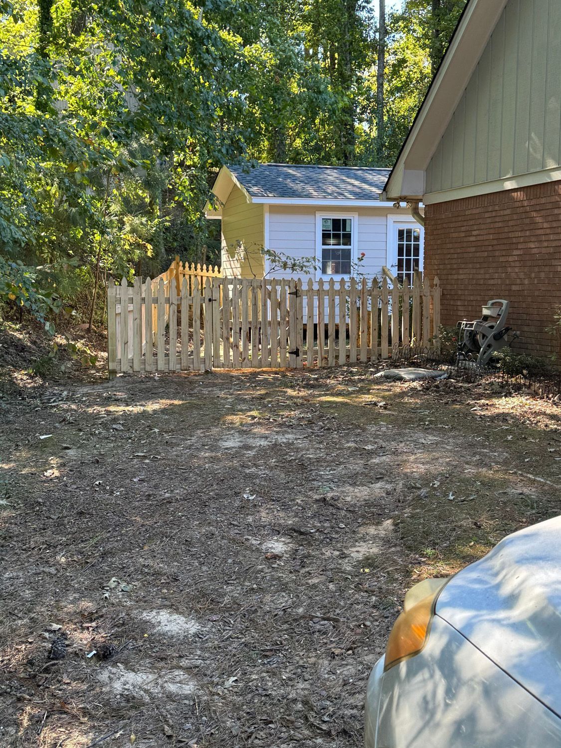 A car is parked in front of a house with a wooden fence.