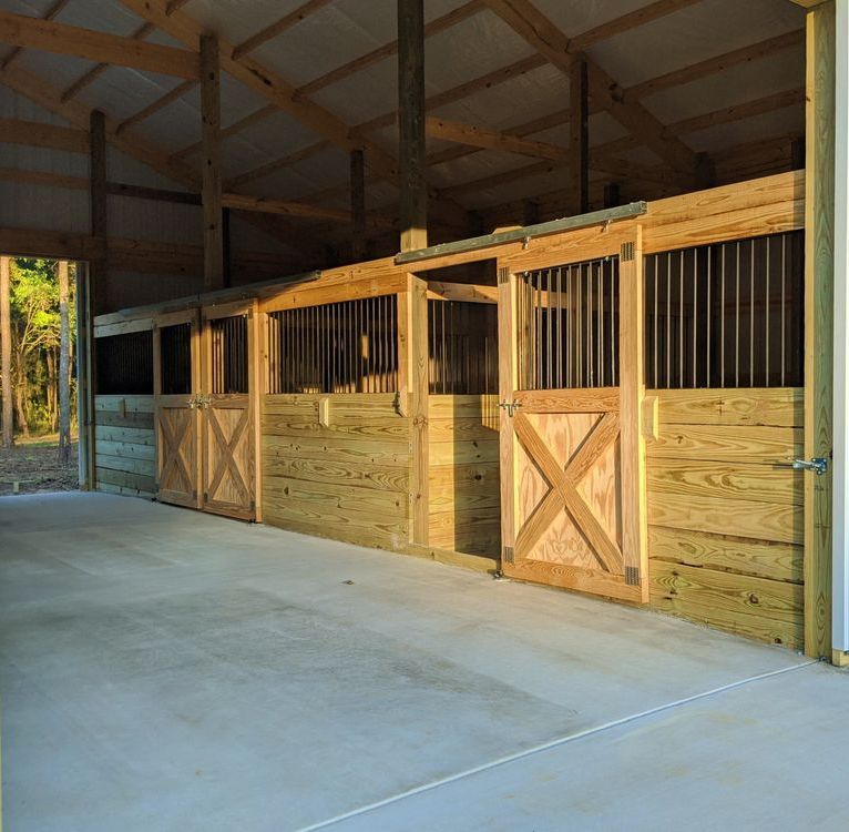 A row of wooden horse stables with a concrete floor