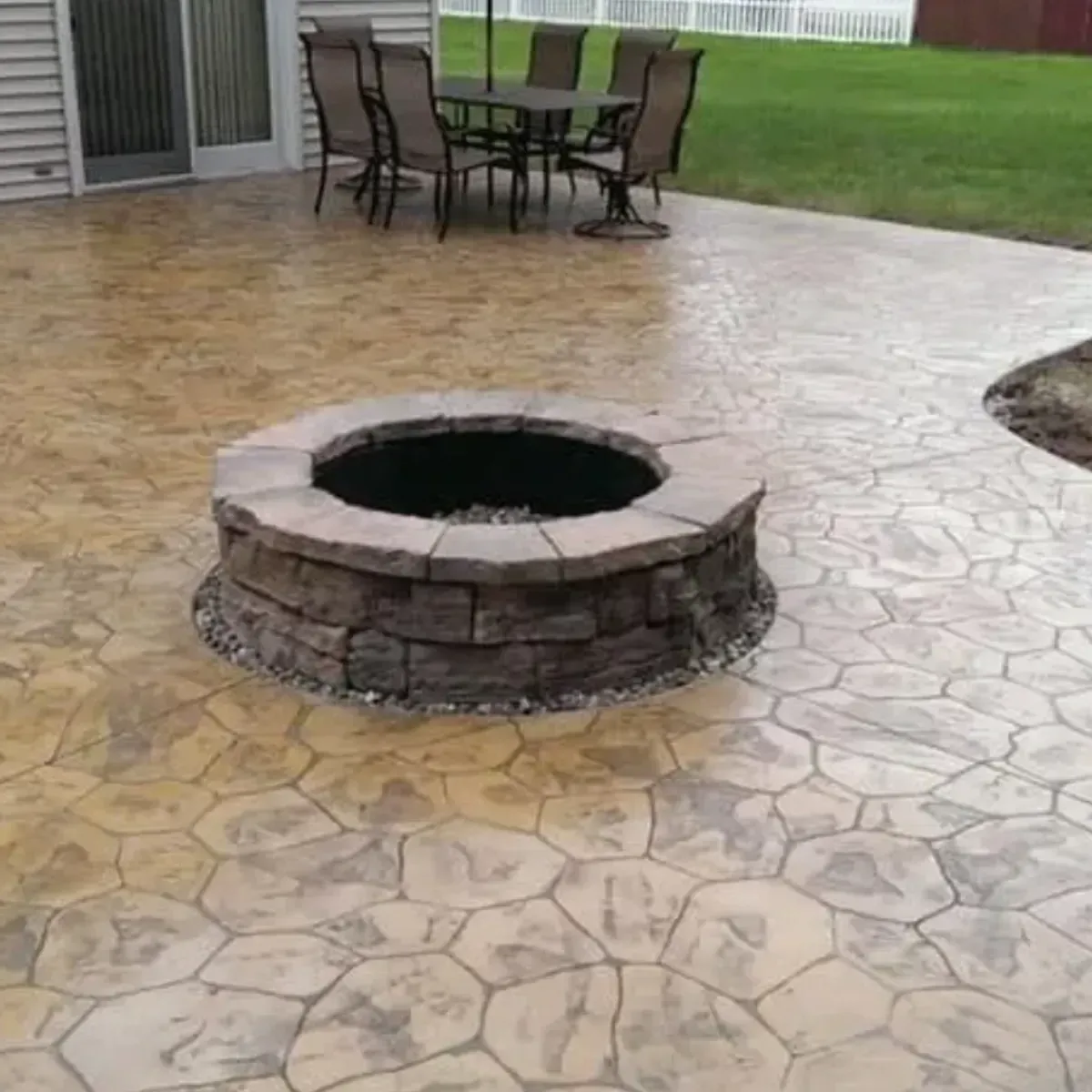 Stone-patterned concrete patio with a fire pit and outdoor dining set.