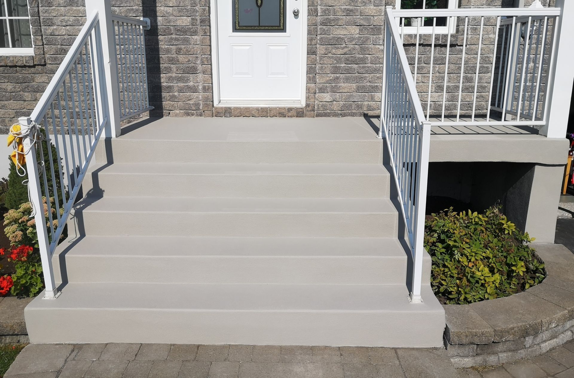 Gray concrete steps leading up to a white door with white railing on either side.