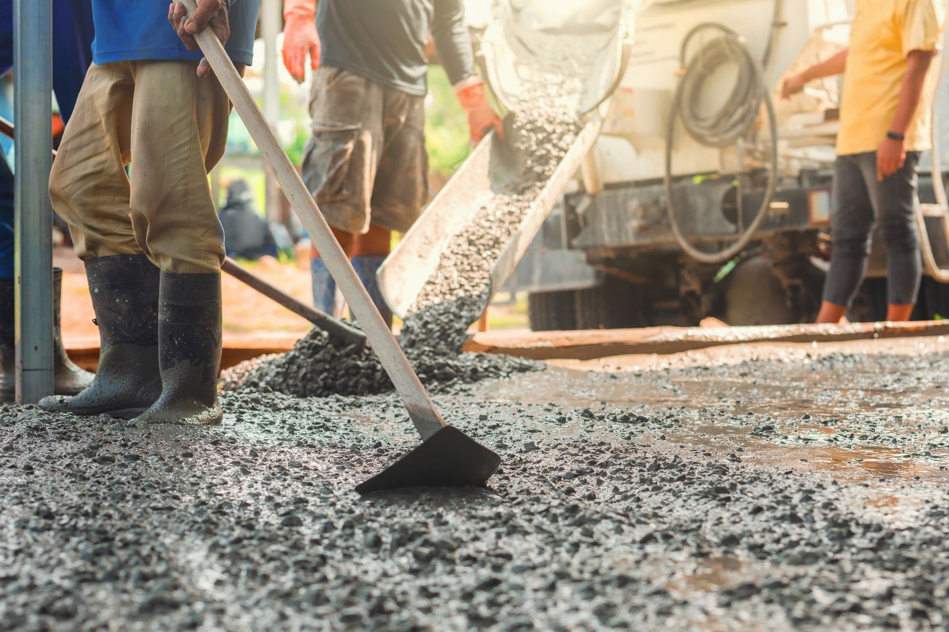 Construction workers pouring and smoothing concrete.