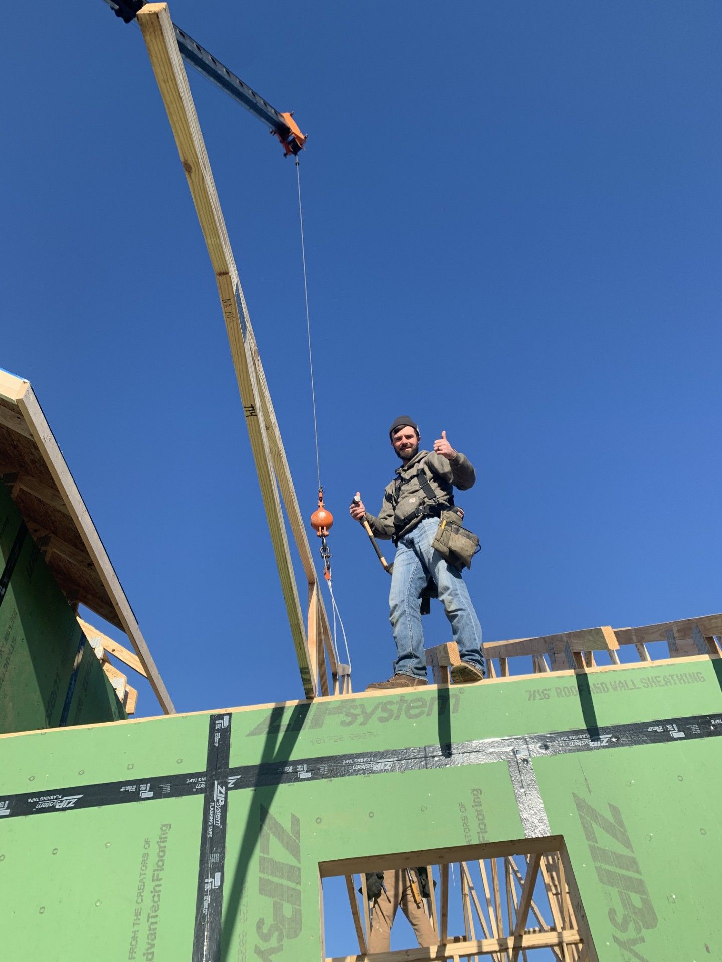 A man is standing on the roof of a building holding a crane.