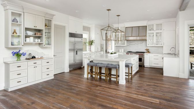 A kitchen with white cabinets , hardwood floors , and stainless steel appliances.