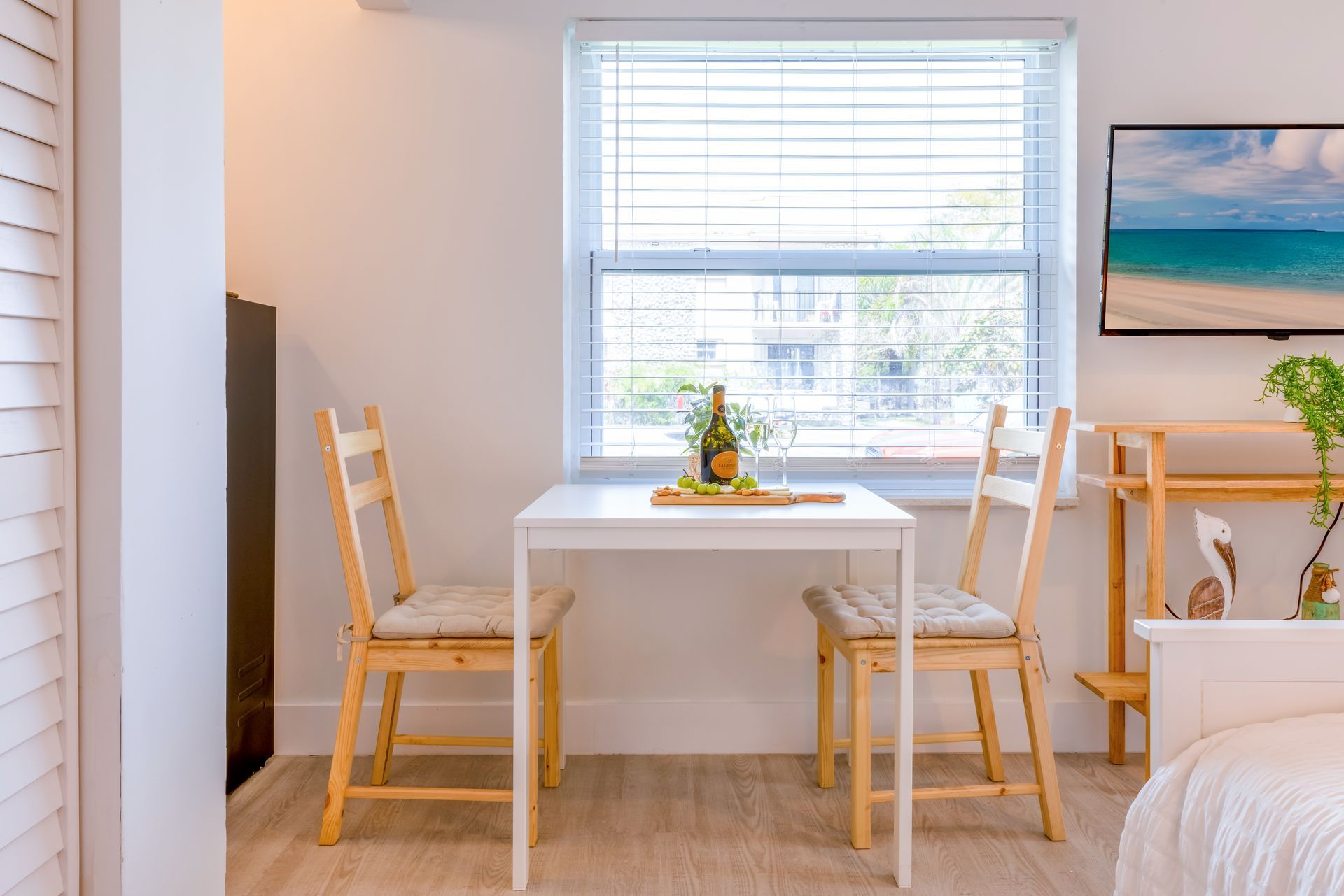 Small dining area with white table, wooden chairs, window, and decorations.