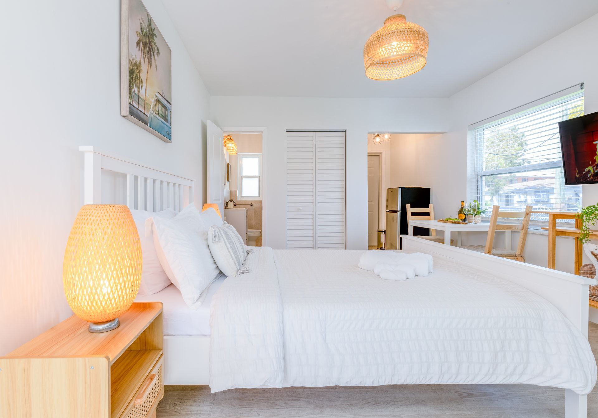 White bedroom with bed, lamp, and table.