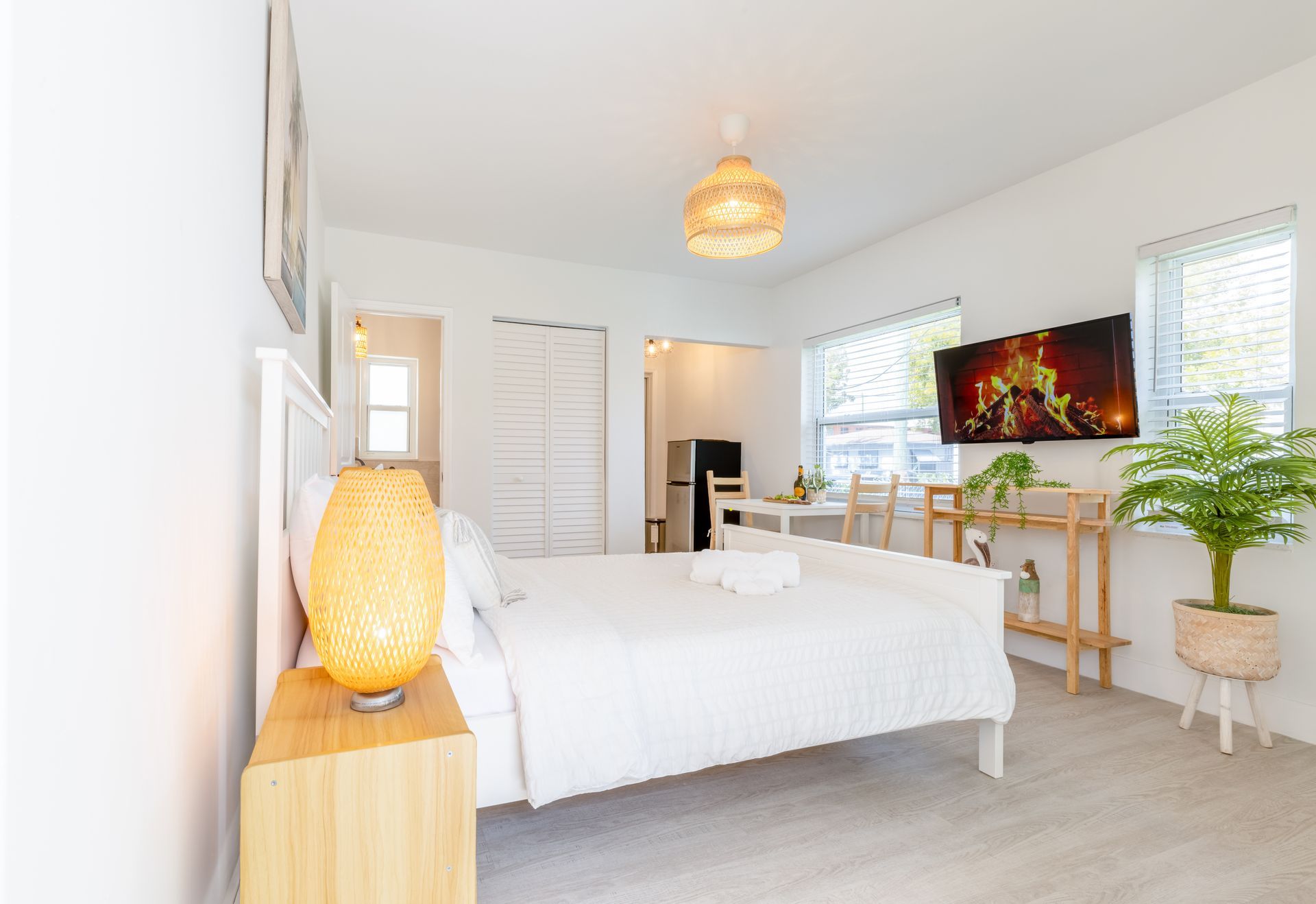 White bedroom with a bed, television, and wooden furniture.