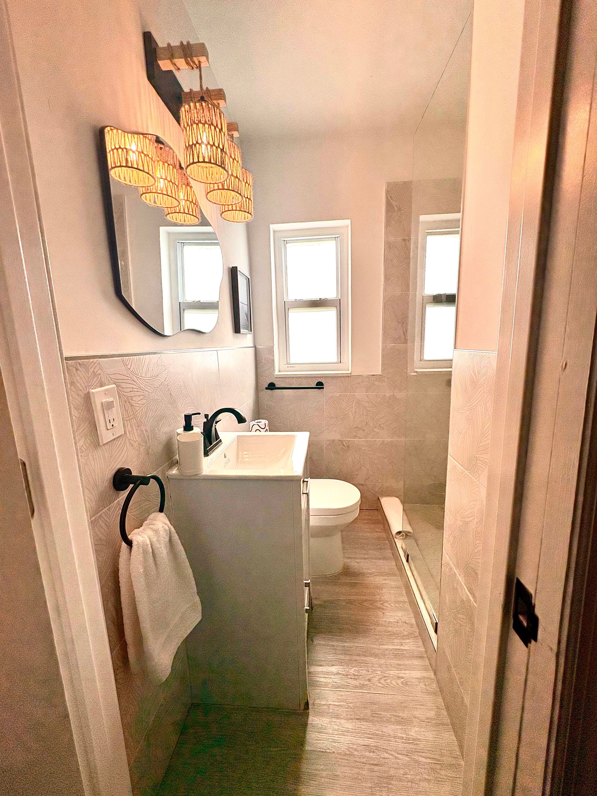 Small bathroom with a sink, toilet, mirror, and a decorative light fixture.