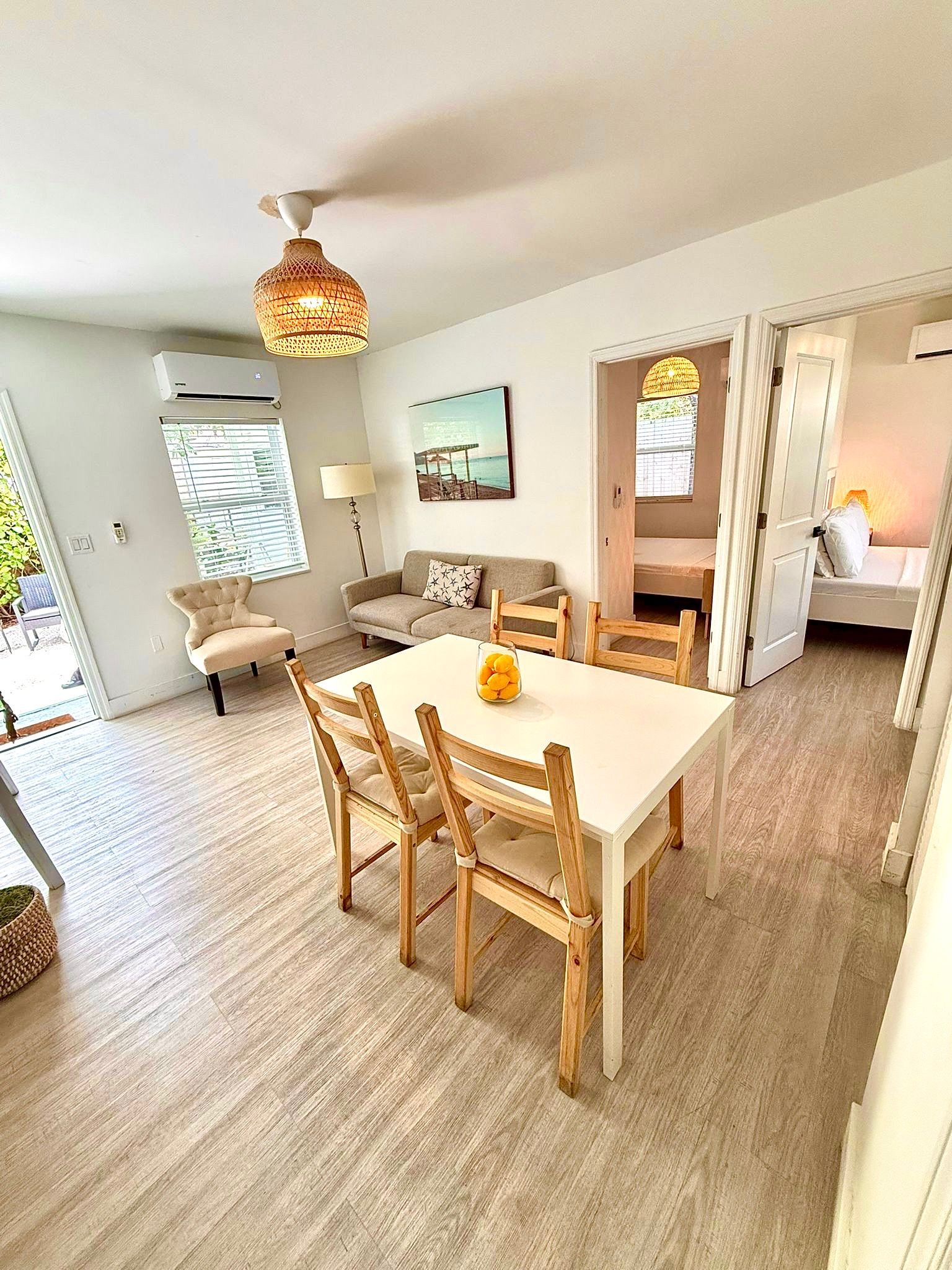 Bright dining area with white table, four chairs, and open doorways to other rooms.