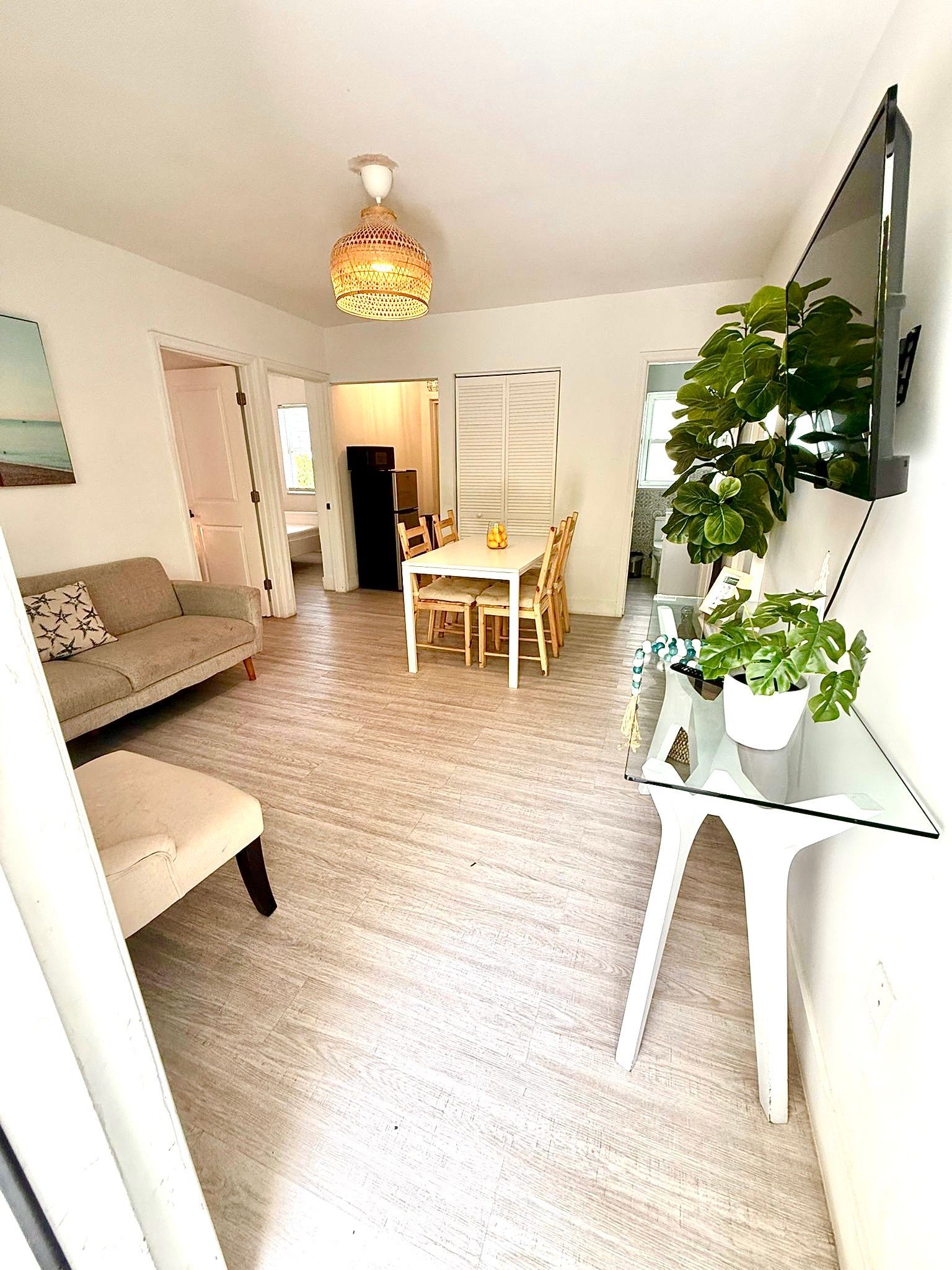 Bright living area with sofa, dining table, TV, and plants.