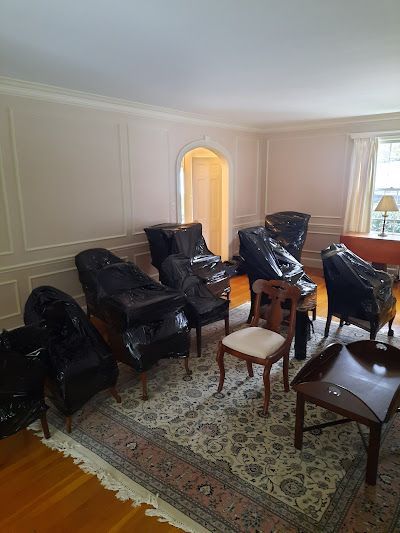 A living room filled with furniture wrapped in plastic.