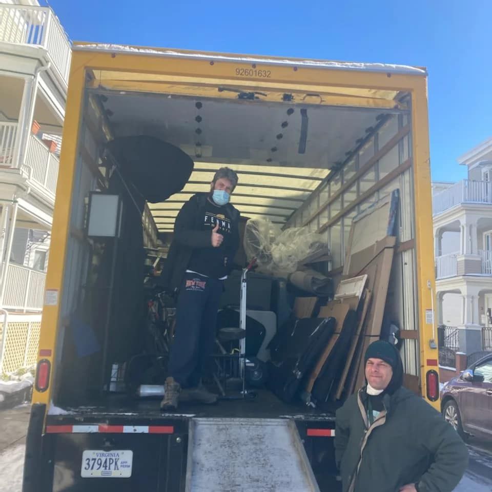 A man wearing a mask is standing in the back of a moving truck