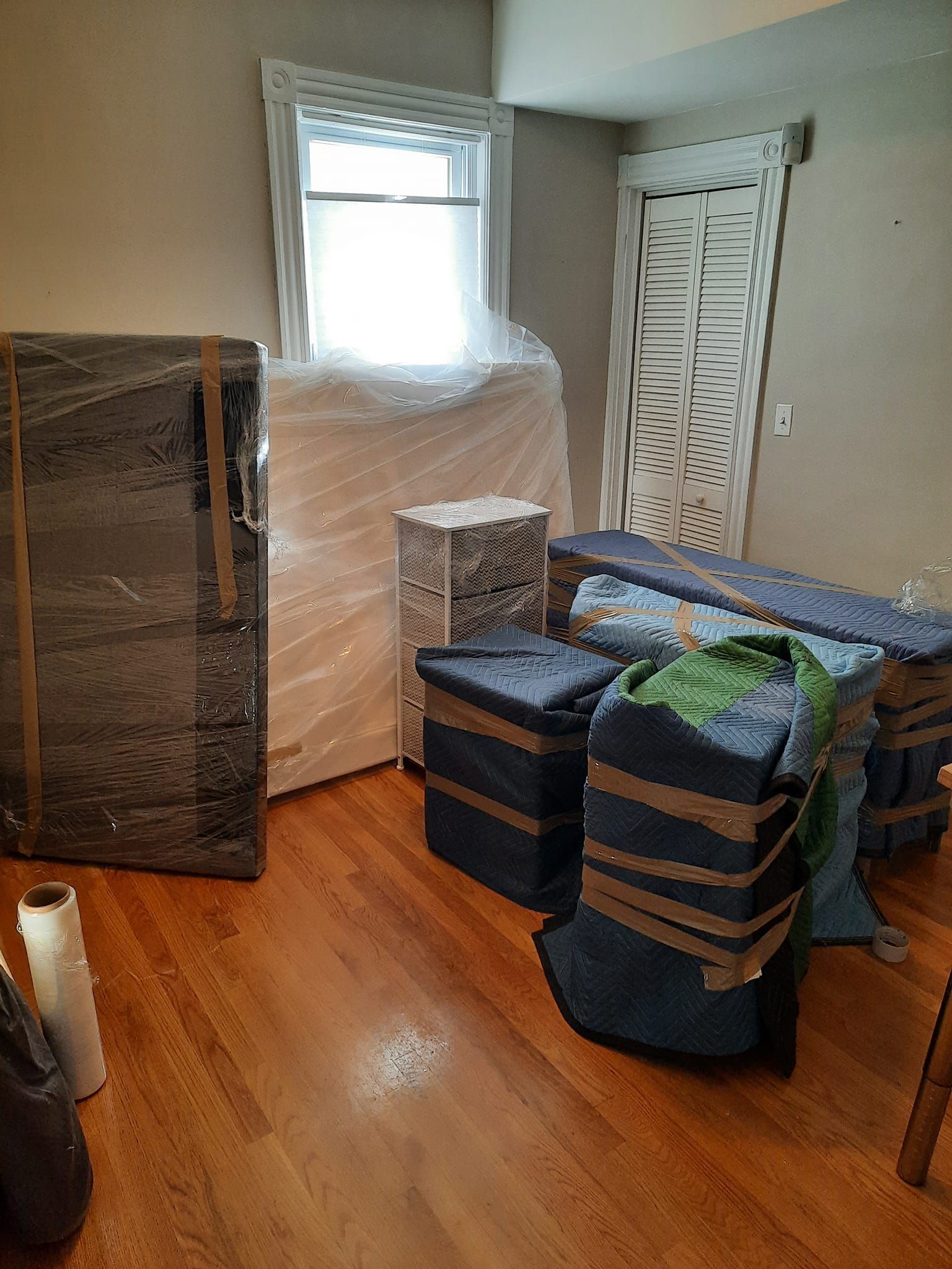 A living room filled with furniture and boxes wrapped in plastic.