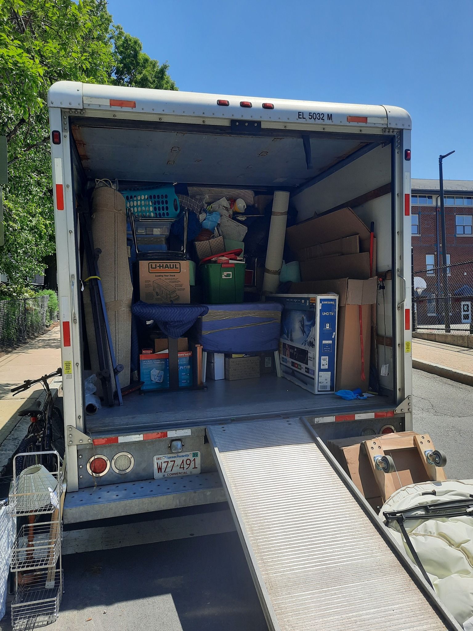 The back of a moving truck is filled with boxes and furniture.