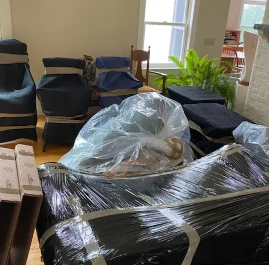 A living room filled with furniture wrapped in plastic