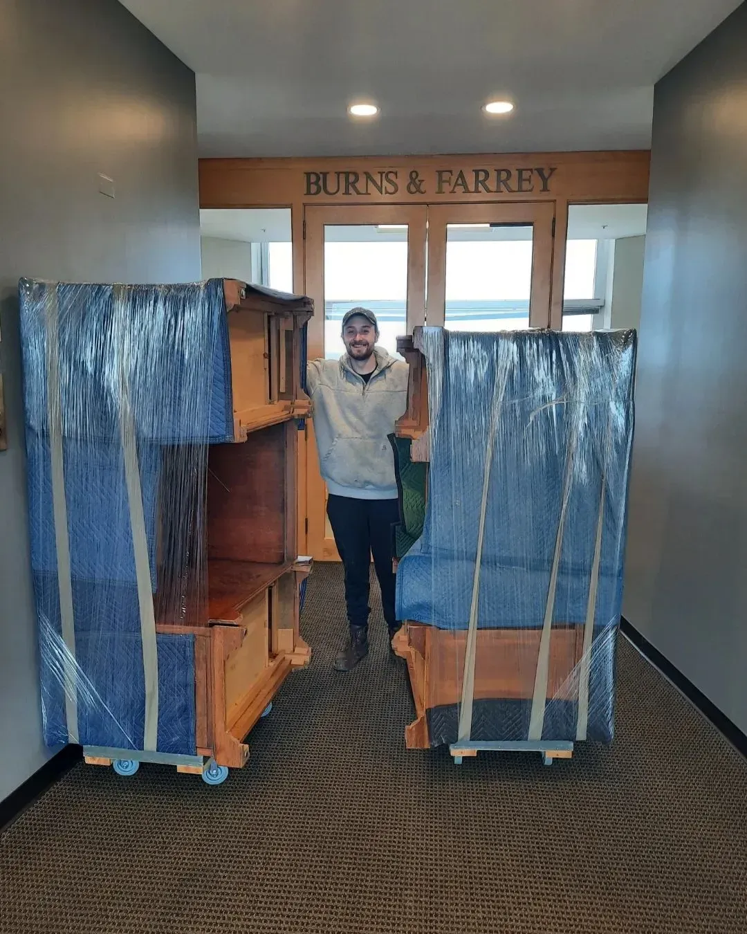 A man is carrying a large piece of furniture in a hallway.