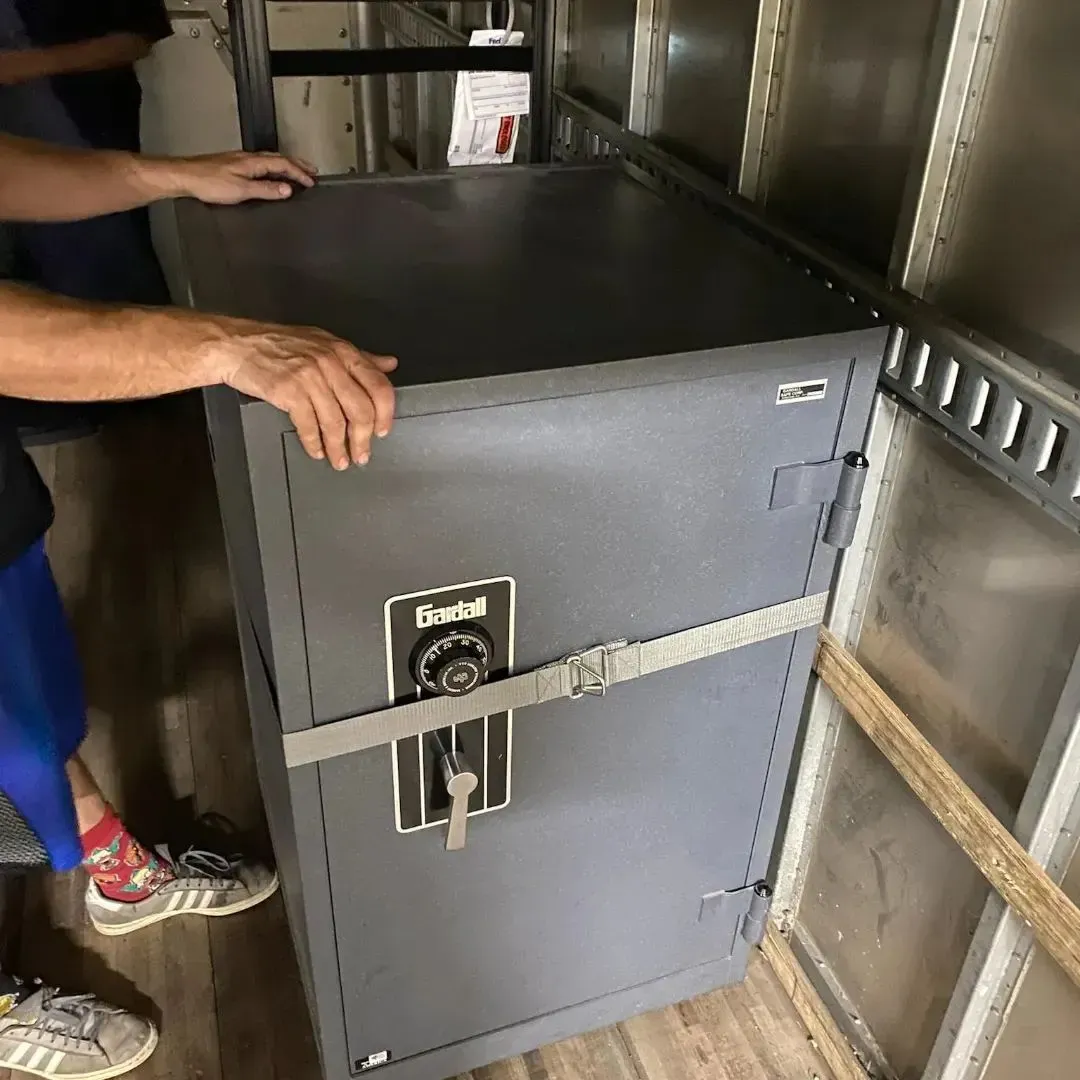 A man is standing next to a safe in a truck.
