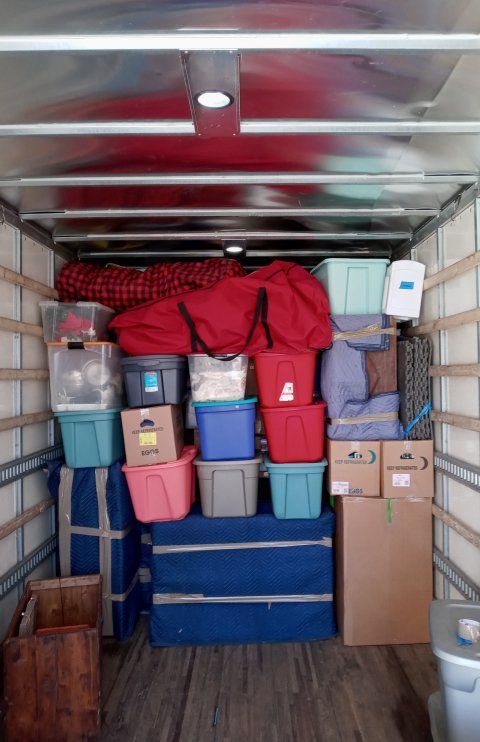 The inside of a moving truck filled with boxes and bins