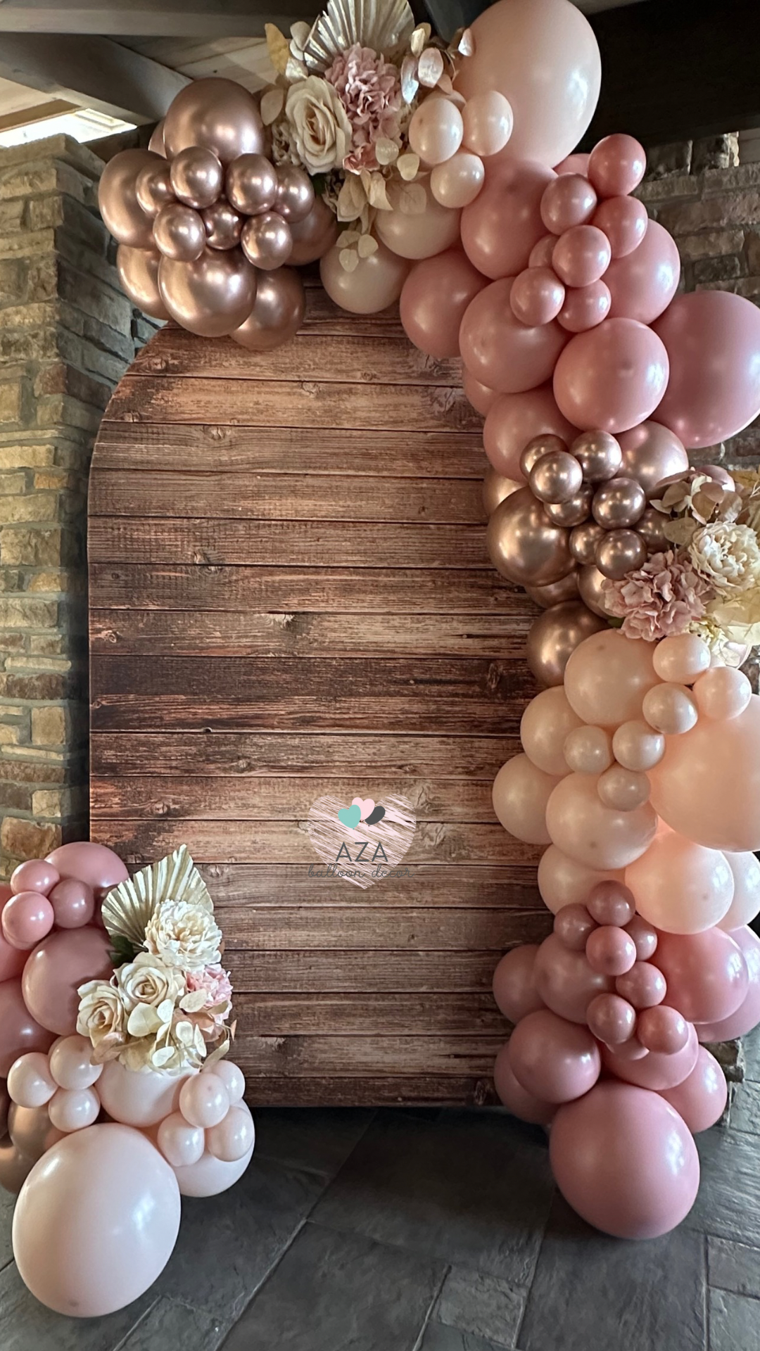 A bunch of pink and white balloons are sitting on a wooden floor.