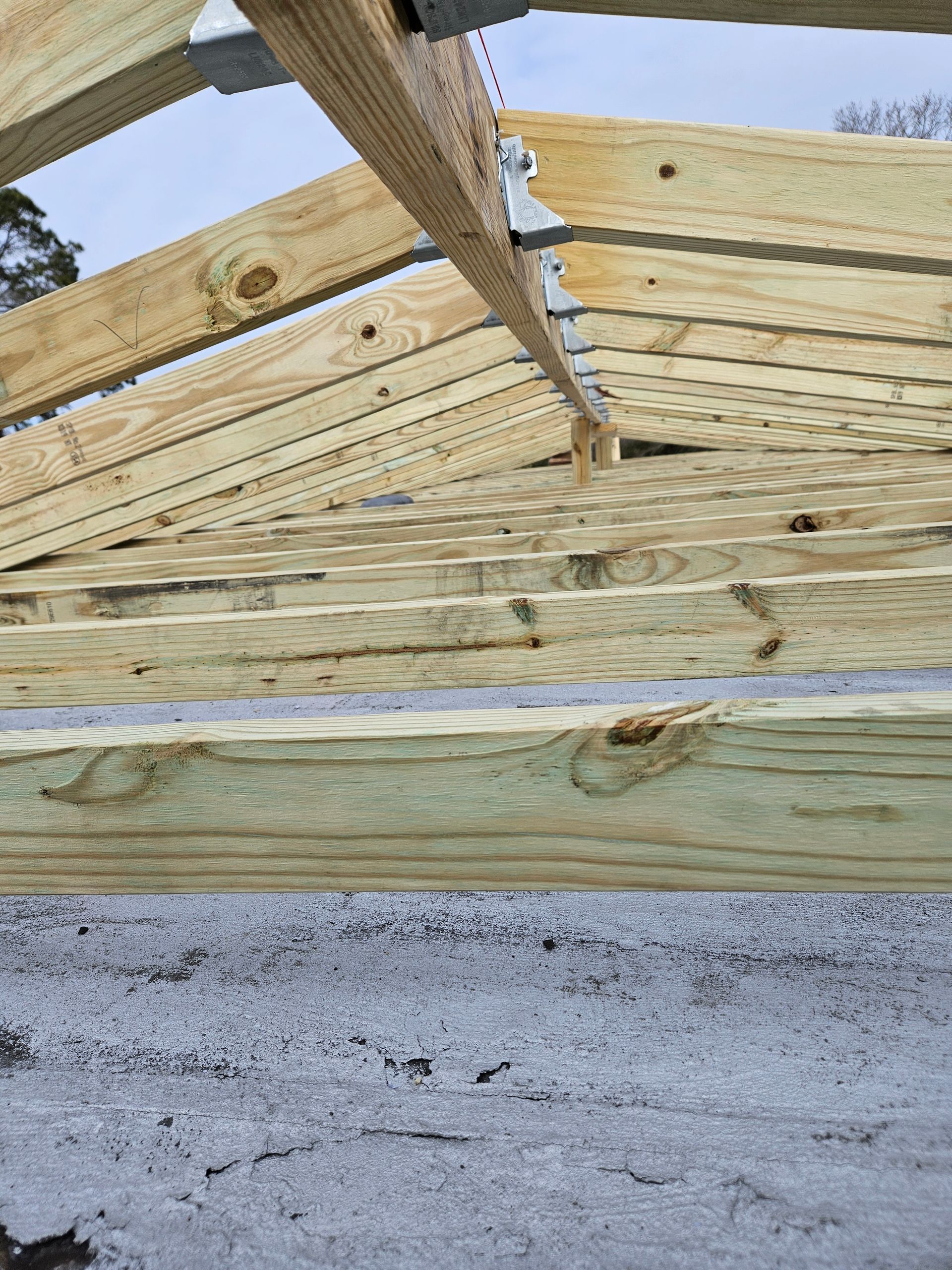 Wooden roof frame under construction with gray support brackets.