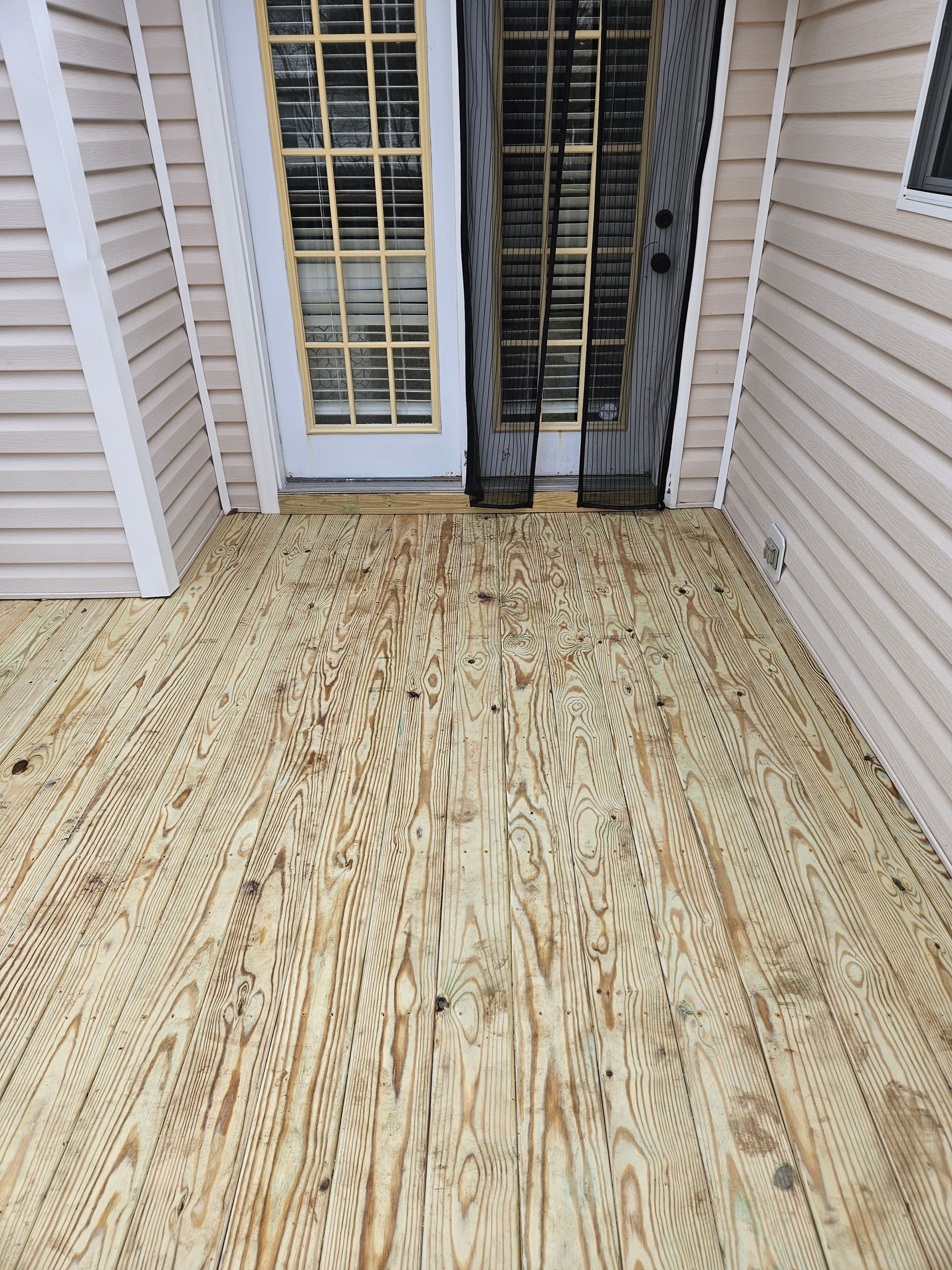 Two workers smoothing wet concrete driveway near a two-story brick house.
