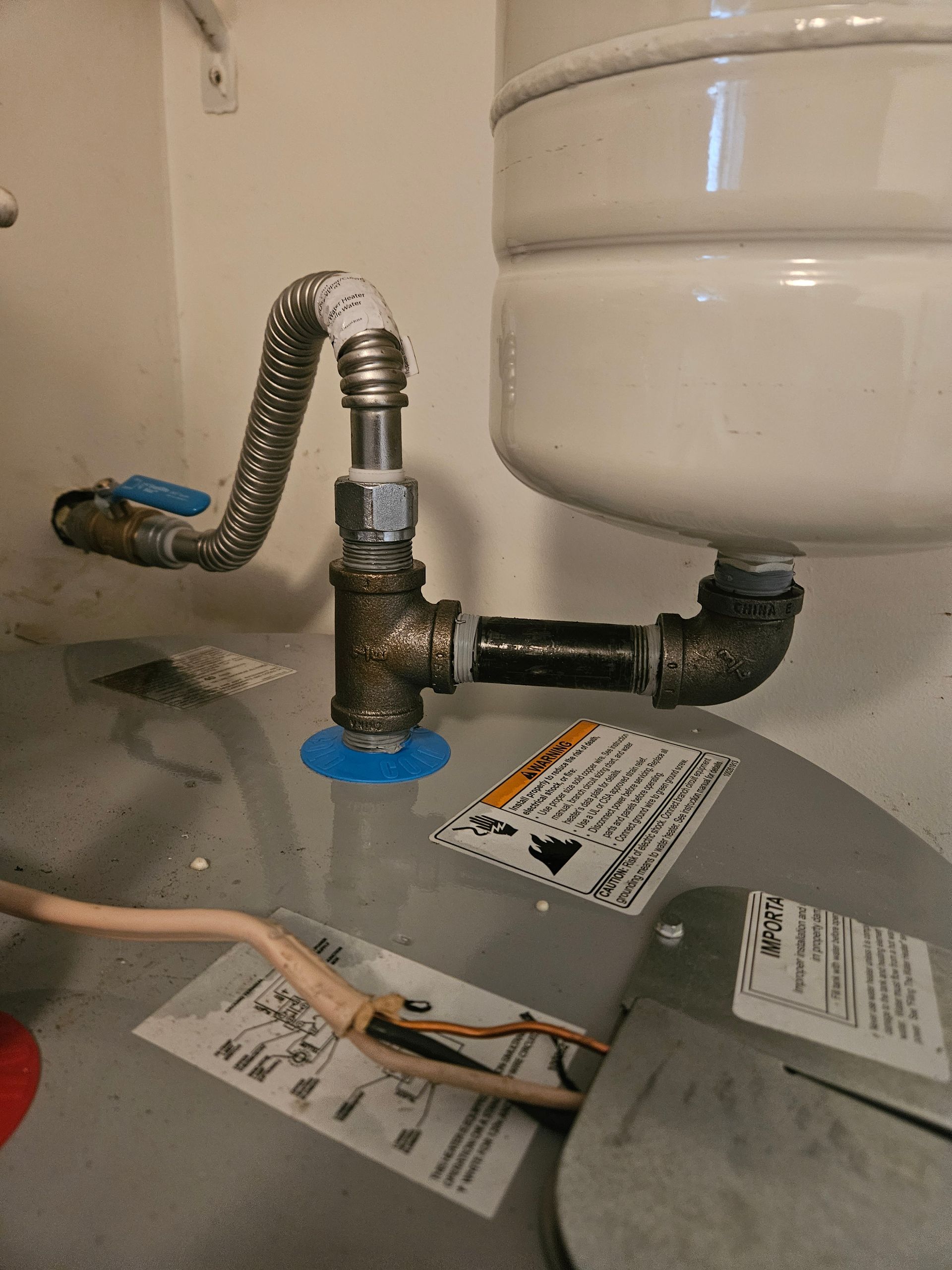Water heater with plumbing, including a flexible gas line and expansion tank.