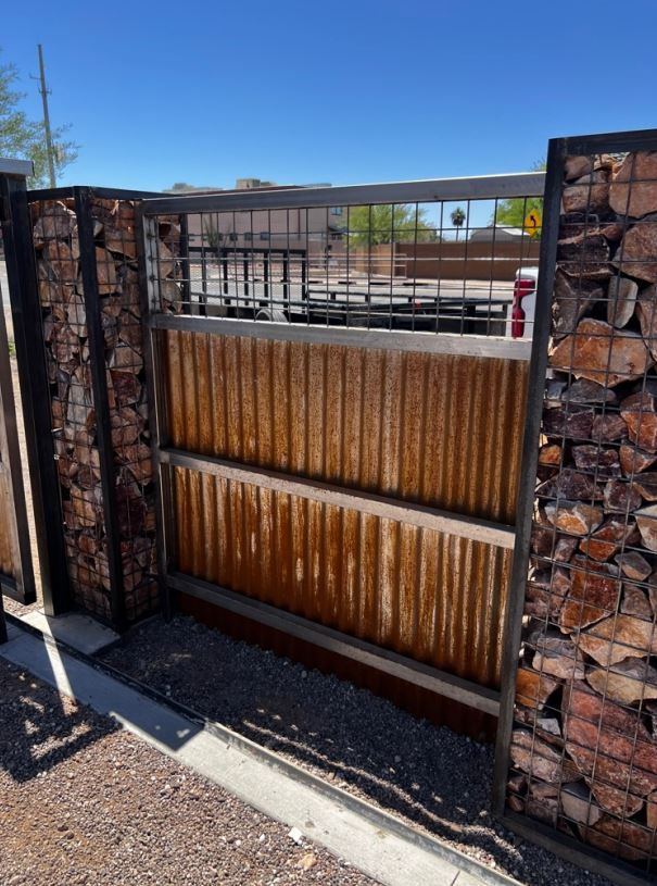 A rusty metal gate with a brick wall behind it