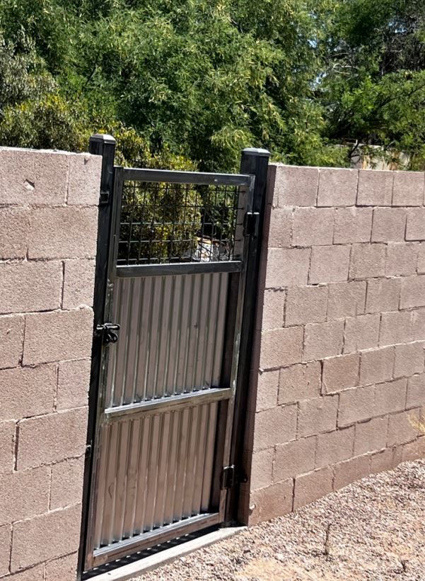 A metal gate is sitting in front of a brick wall.