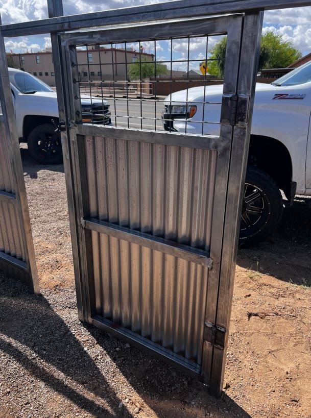 A white truck is parked in front of a metal gate.