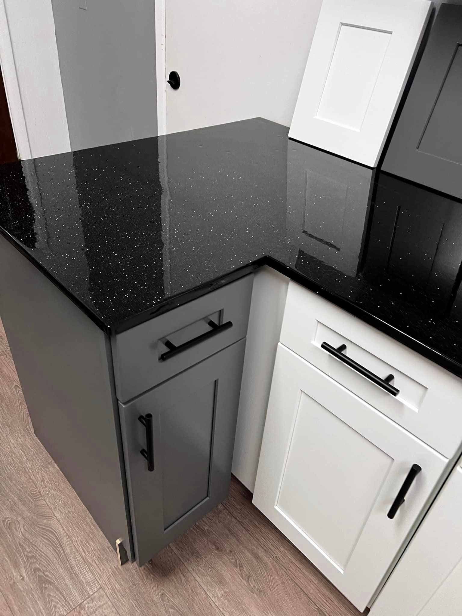 A kitchen with black granite counter tops and white cabinets.