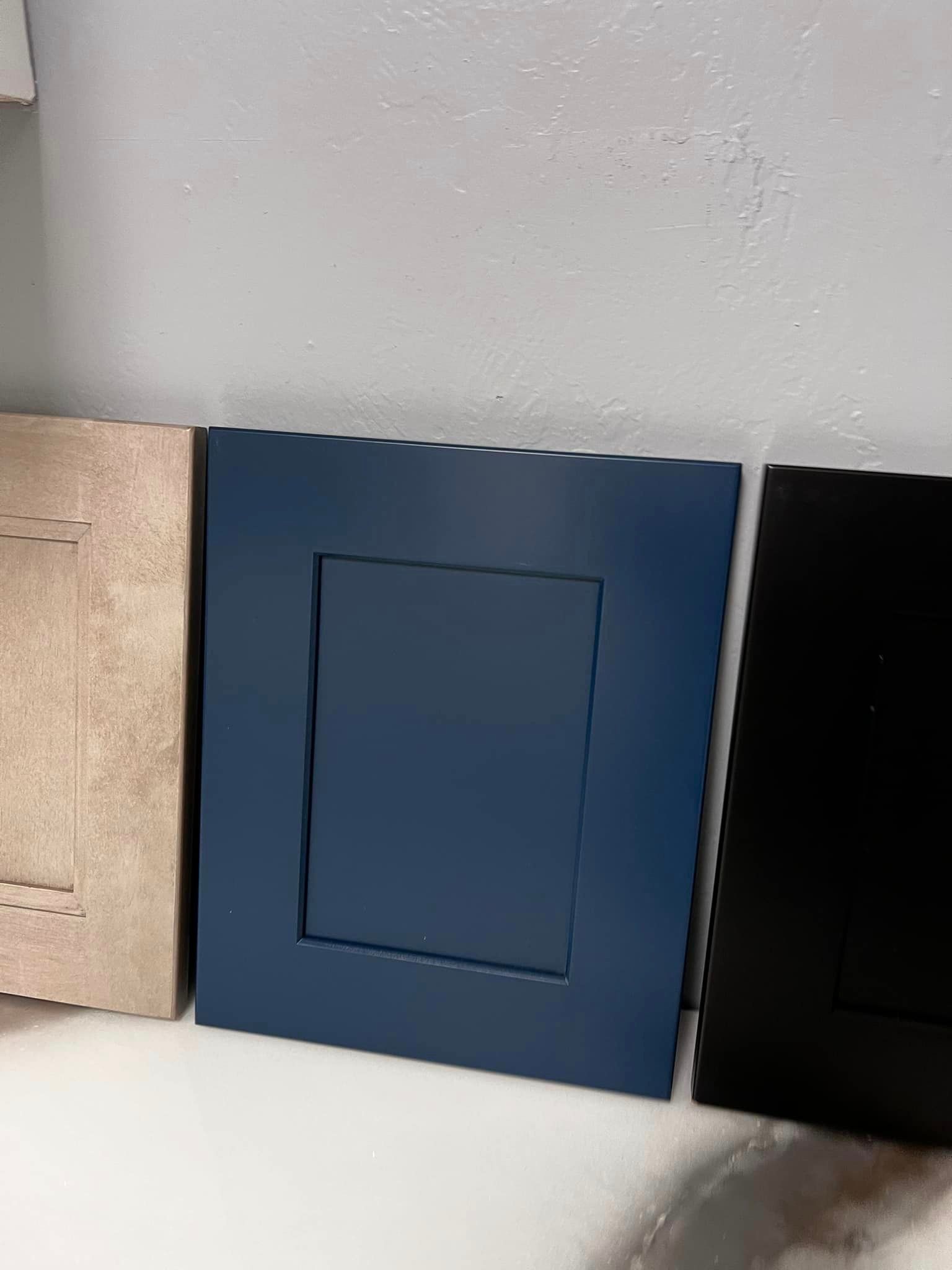 Three different colored cabinet doors are sitting next to each other on a table.