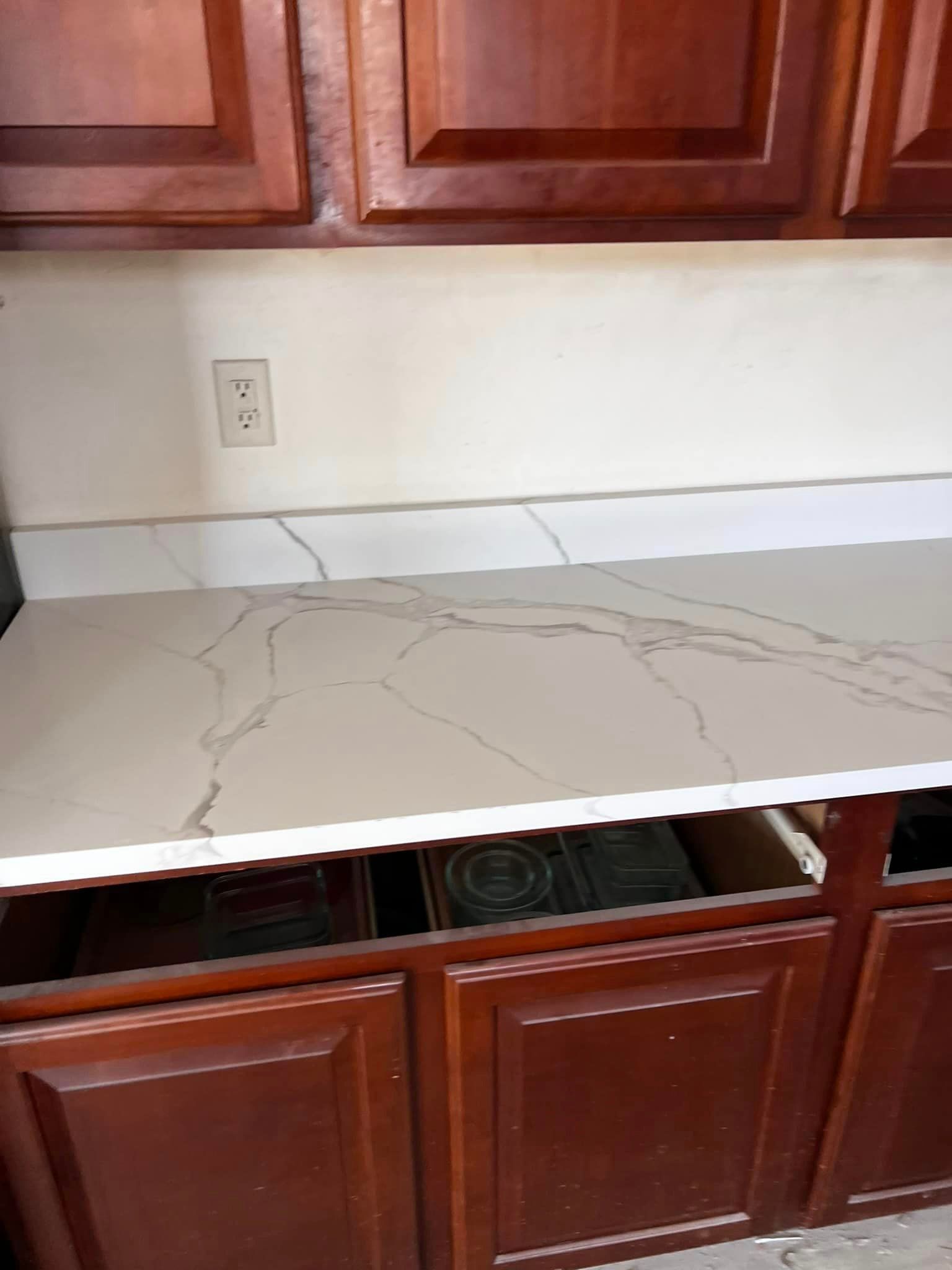 A kitchen counter with a white counter top and wooden cabinets.