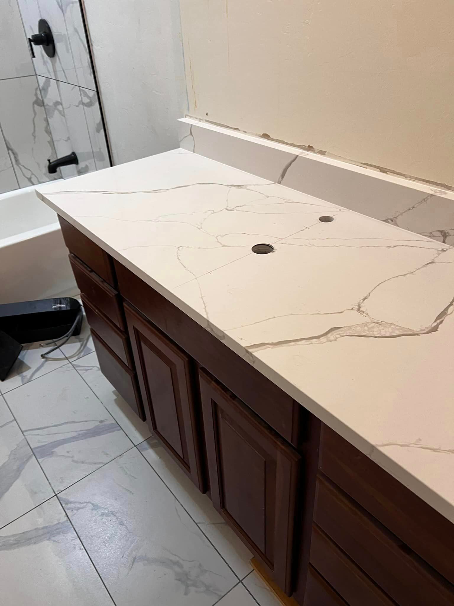A bathroom with a white counter top and brown cabinets.
