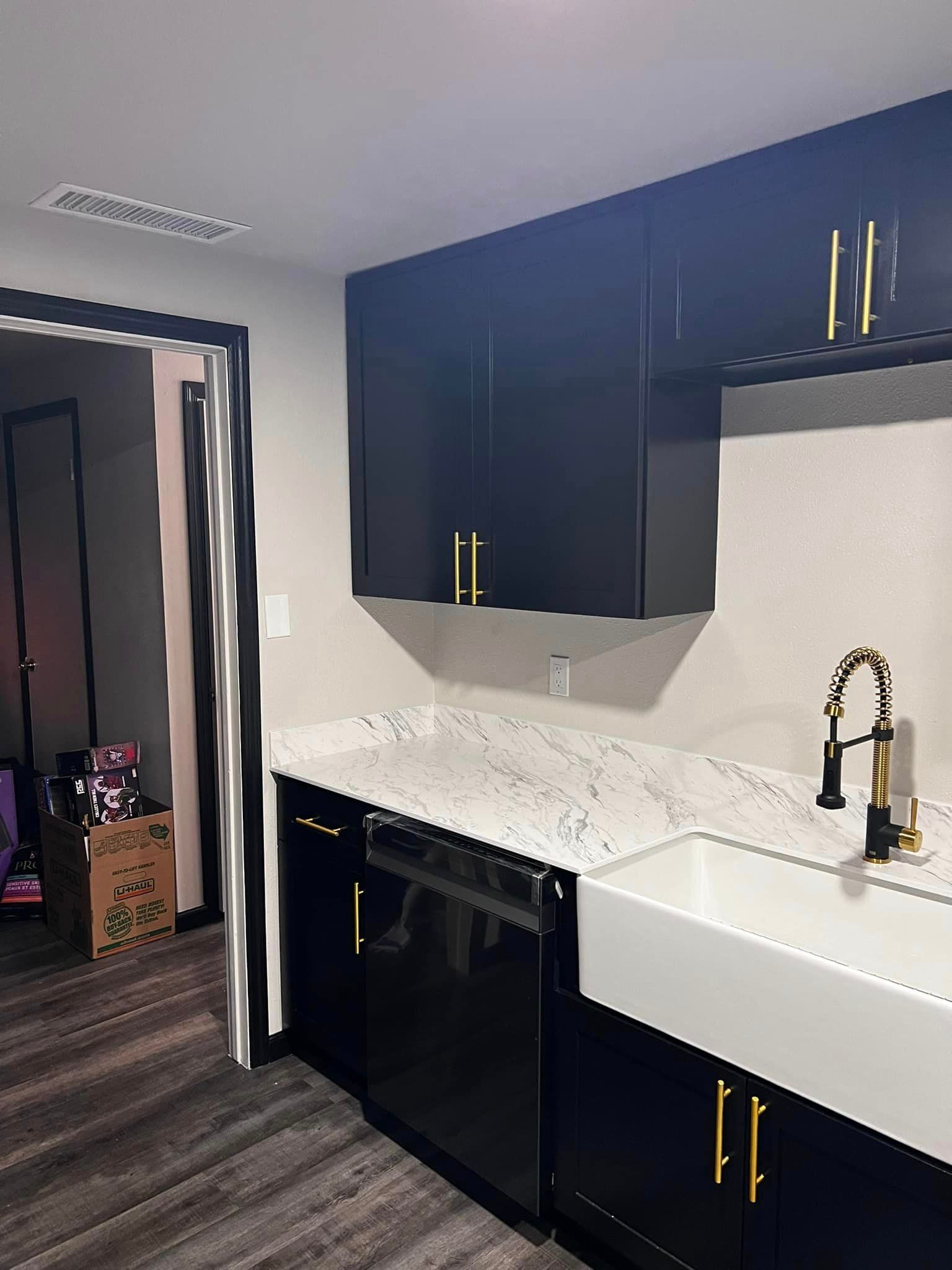 A kitchen with black cabinets and a white sink.