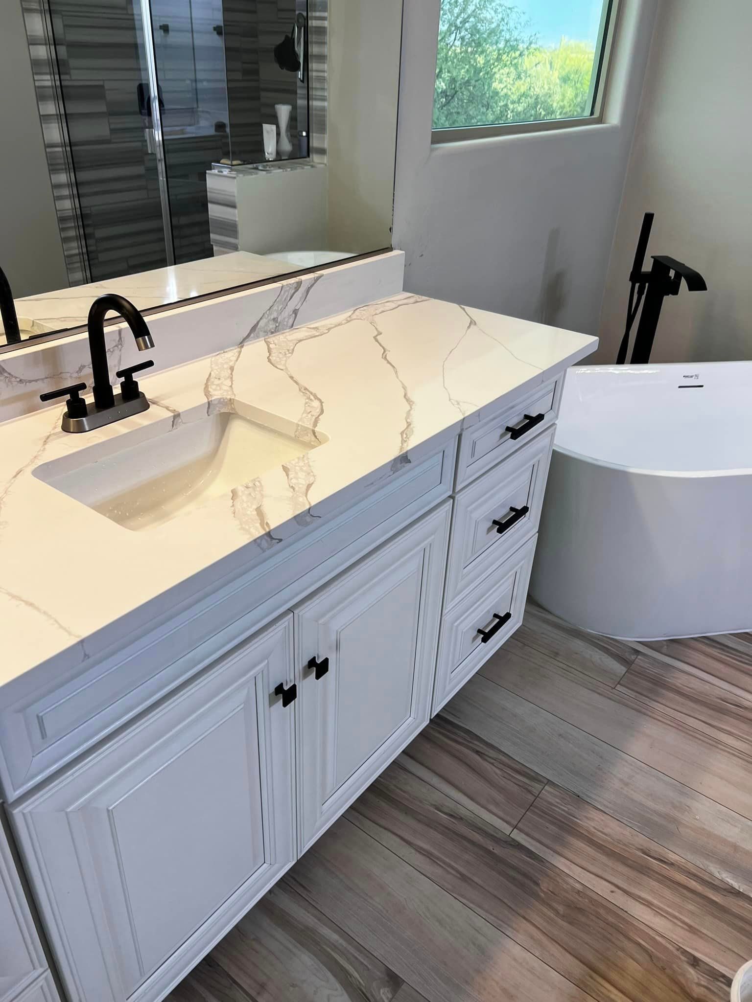 A bathroom with a sink , tub and mirror.